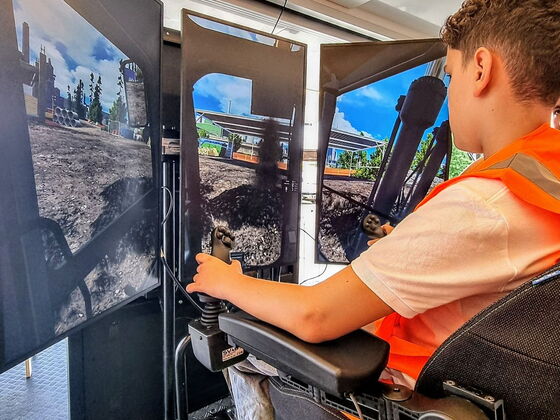 Ein Schüler in Warnweste sitzt in einem Baggersimulator