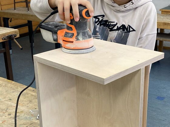 Ein Schüler schleift mit einer Schleifmaschine