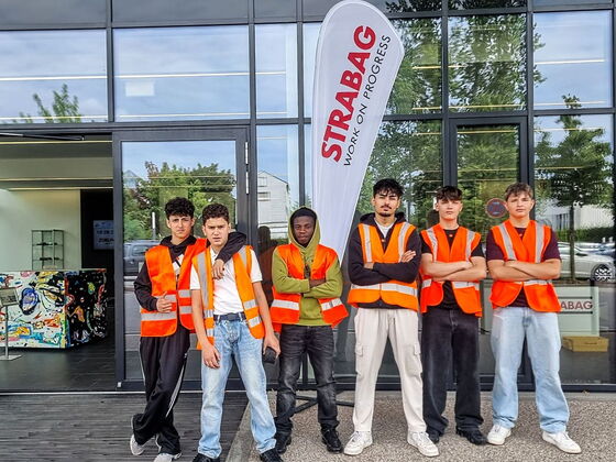 Sechs Schüler in Pose in Warnwesten vor dem Firmeneingang