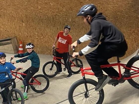 Schüler fahren mit einem Fahrrad eine Schanze hinab